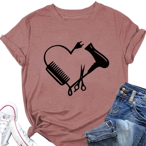 Flachgelegte altrosa T-Shirt mit kreativem Herz-Print aus Friseurwerkzeugen