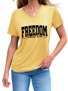 Detailed view of yellow V-neck T-shirt featuring black Freedom and Charlie Kirk text