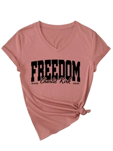 Close-up of pink V-neck T-shirt detail showing the knotted hem and Freedom text print