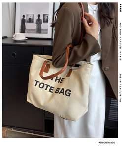 Chic beige canvas tote bag with brown leather handles worn by model in a stylish setting