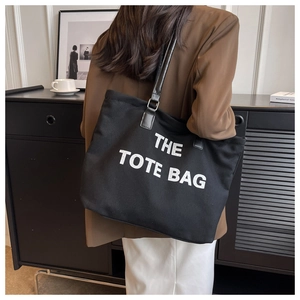 Rear view of model wearing a black canvas tote bag with adjustable leather straps