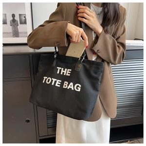 Lifestyle shot of large black canvas tote bag with white THE TOTE BAG print for women