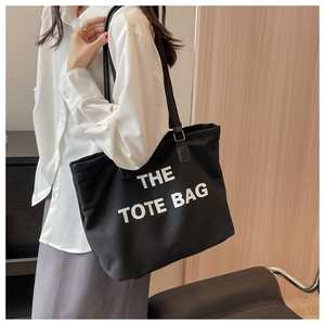 Large black canvas tote bag with white text print shown on a female model