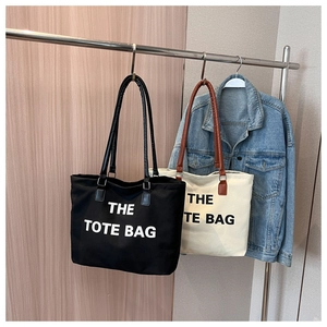 Detail view of canvas tote bags with contrast leather handles and bold text printing