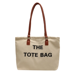 Minimalist canvas tote bag with leather handles and bold black text on a white background