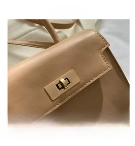 Détail du fermoir tournant doré sur un sac à bandoulière en similicuir beige élégant