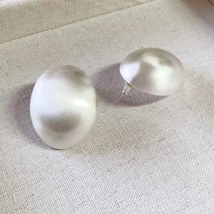 Boucles d'oreilles ovales argentées minimalistes avec finition mate sur texture grise