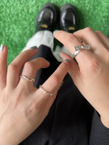 Close-up of stacked silver bow, infinite loop, and bead rings on fingers for styling
