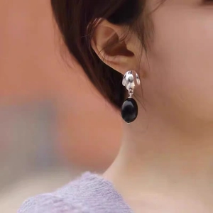 Teardrop black onyx earrings with 925 silver needle, worn by a model in a close-up view