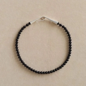 Vue détaillée d'un collier de perles d'onyx noires avec un fermoir en S en argent brillant