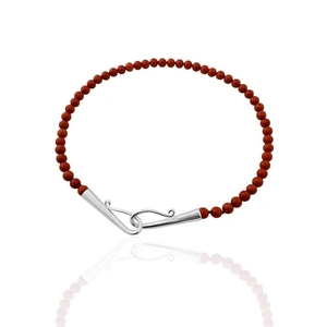 Gros plan d'un collier artisanal en perles brun rouge avec fermoir à crochet en S argenté