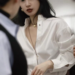 Chemise blanche minimaliste assortie d'un long collier avec pendentif cylindre doré