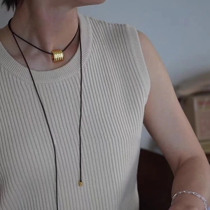 Collier chic avec pendentif cylindre doré sur cordon en cuir porté par un modèle