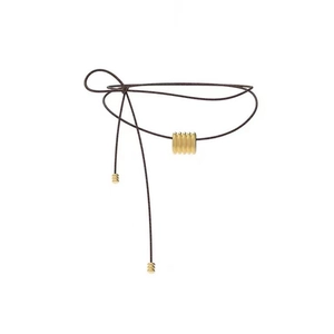 Détail d'un collier en cordon tressé marron réglable avec une perle dorée mate texturée