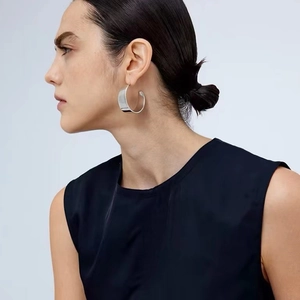 Boucles d'oreilles créoles argentées en C portées par un mannequin femme