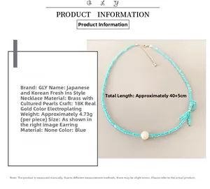 Detail of beaded necklace with blue beads, white cultured pearl and bow accent