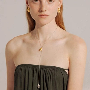 Collier en Y moderne graine et boucles d'oreilles dorées texturées sur un mannequin