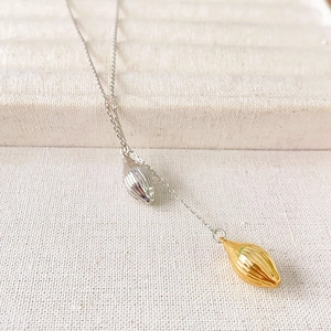Collier minimaliste en forme de graine de plante en finitions or et argentées