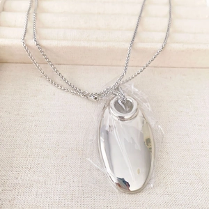 Minimalist silver oval pendant necklace with a polished mirror finish on thin woven chain