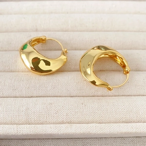 Chic irregular thick gold hoop earrings with polished finish on beige jewelry display