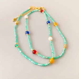 Collana artigianale con perle di lapislazzuli e agata su uno sfondo grigio neutro