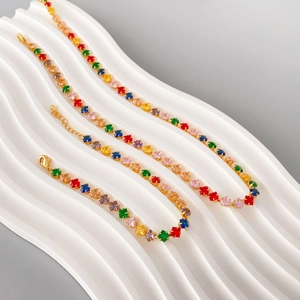 Rainbow cubic zirconia 18K gold-plated necklace and bracelet set on a white wavy pedestal
