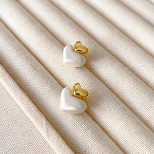 Boucles d'oreilles double cœur bicolore or et argent sur un plateau à bijoux chic