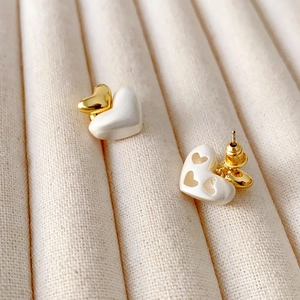 Boucles d'oreilles cœur en métal brossé bicolore or et argent sur un plateau de bijoux