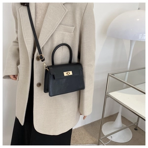 Détail du sac à main en cuir noir mat avec fermoir doré et bandoulière amovible réglable