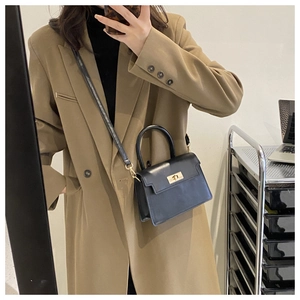 Selfie miroir montrant le sac trapèze noir avec fermoir doré porté en bandoulière chic