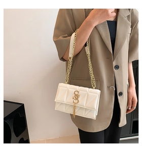 Detail of white quilted crossbody bag with golden chain and double S logo with tassel
