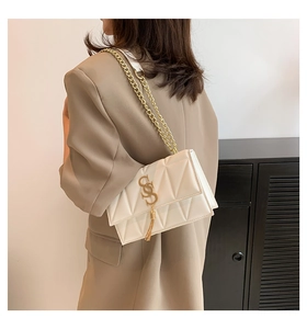 White quilted crossbody bag with gold chain strap and tassel detail shown on a model