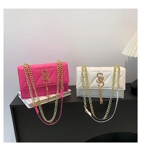 Detail of pink and white quilted flap bags with gold chain straps and letter S pendants