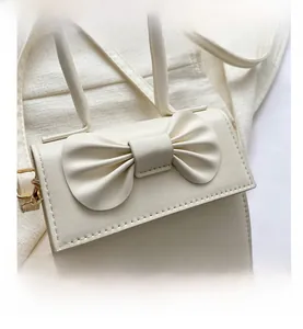 Detail of cream white leather mini bag featuring a decorative bow and fine stitching