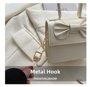 Detail of the golden metal hook and adjustable shoulder strap on the off-white bag