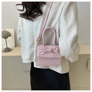 Mini borsa rosa con grande fiocco indossata da una modella in un contesto lifestyle