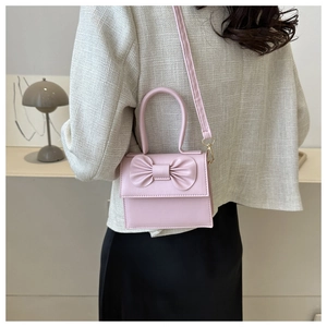 Dettaglio della mini borsa a patta rosa chiaro con grande fiocco e tracolla