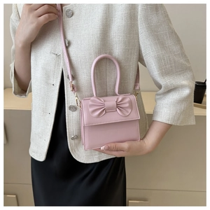 Mini borsa a tracolla rosa con fiocco, indossata da una modella in un interno morbido