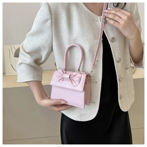 Close-up of pink mini crossbody bag with 3D bow detail and gold-tone hardware on model