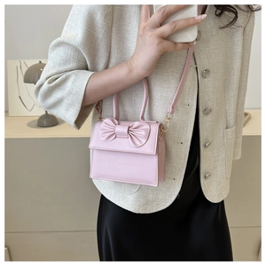 Model wearing a pink PU leather crossbody bag with a cute bow detail and top handle