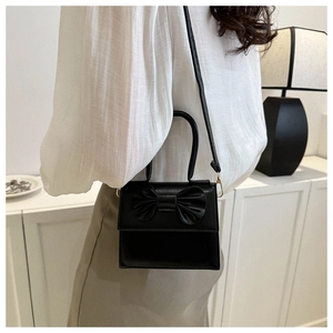 Dettaglio di una mini borsa nera con fiocco 3D sulla patta e manico elegante