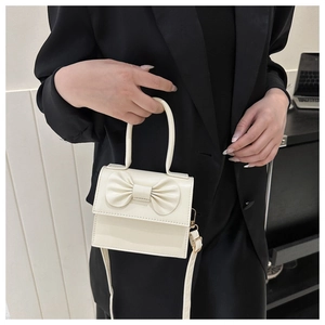 Detail of cream white handbag with a 3D bow decoration on the front flap