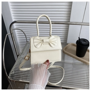 Dettaglio della borsa quadrata bianco crema con decorazione a fiocco e fibbia oro