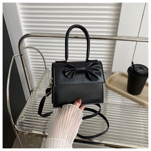 Dettaglio di una borsa nera in pelle PU opaca con un fiocco elegante e manico superiore
