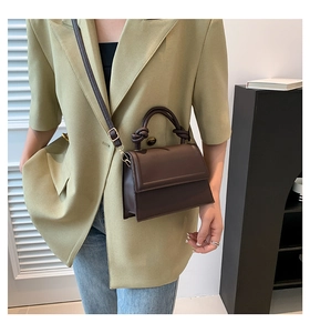 Detailed view of coffee brown crossbody bag with knotted handle and gold hardware