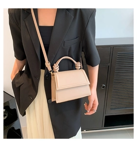 Détail d'un sac bandoulière beige en cuir avec poignée nouée porté par un mannequin