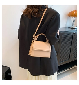 Detail of minimalist beige crossbody bag featuring knotted handle and matte leather finish