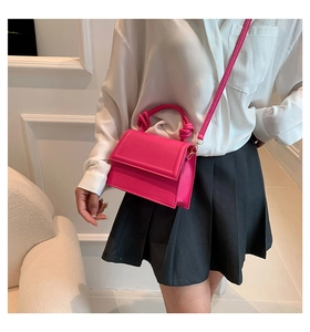 Detail of rose red square handbag featuring a knotted handle and microfibre leather texture