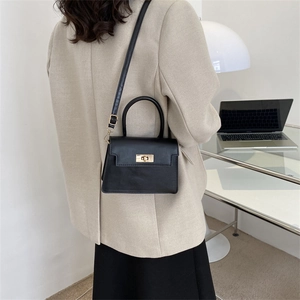 Petit sac à main noir élégant avec fermoir doré porté par un mannequin