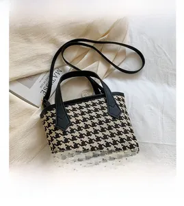 Detail of houndstooth bucket bag with leather handles on artistic magazine background